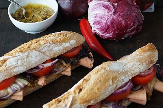 Baguette mit einer Senf-Dattel-Crème, in Knoblauch geschmortem Radicchio, Tomaten und roter Zwiebel und CHILI EXTRA Aufschnitt